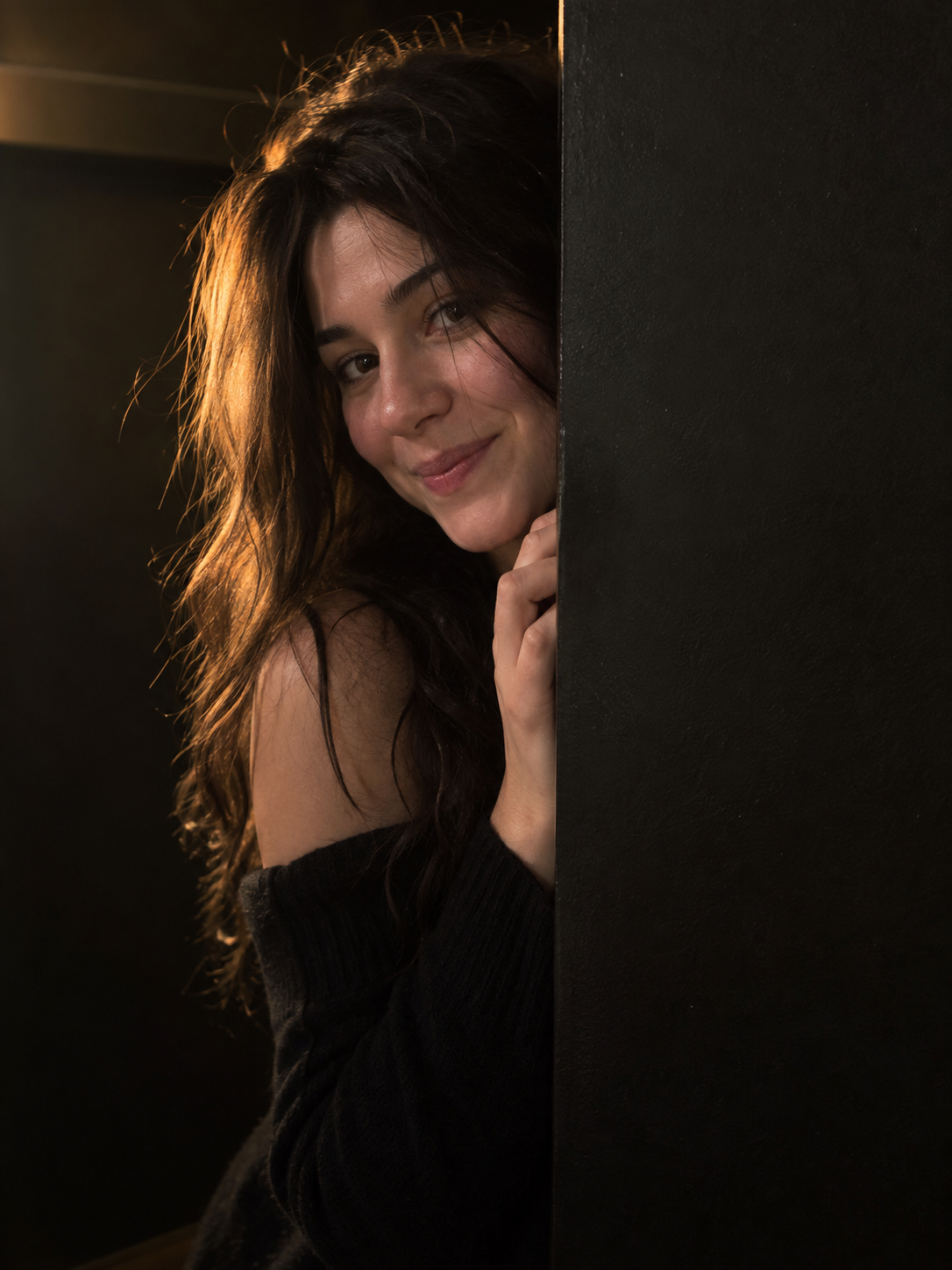 Example of a warm natural phone portrait of an adult woman peeking from behind a black partition
